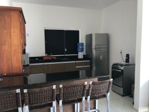 una cucina con un bancone con sedie e un frigorifero di Casa condomínio fechado Paripueira a Paripueira