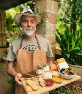 Un uomo con un cappello che tiene un vassoio di cibo di Masseria Borgo del Gallo a Tricase