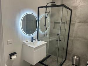 une salle de bain avec une douche, un lavabo et un miroir dans l'établissement Northcott Lodge, à Adamstown 23 autres photos