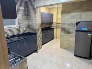 a kitchen with black cabinets and a sink and a refrigerator at 4شارع نبلس المهندسين in Cairo