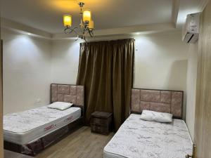 a bedroom with two beds and a chandelier at 4شارع نبلس المهندسين in Cairo
