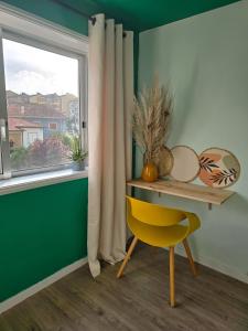 a table and a yellow chair in a room with a window at The House of Cats in Oliveira do Douro