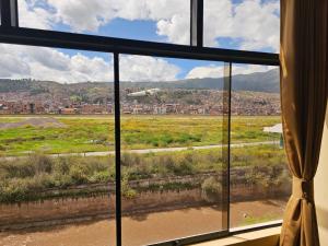 a window with a view of a field and a city at Luxury apartment in Cusco