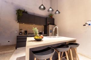 a kitchen with a counter with a sink and stools at Alma Tropical - 4 Unit Luxury Villa Experience Santa Teresa in Santa Teresa Beach