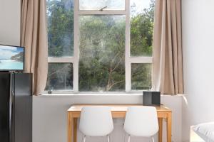 einem Esstisch mit zwei weißen Stühlen vor einem Fenster in der Unterkunft Perfectly Located Studio by Rushcutters Bay Park in Sydney