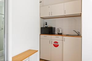 eine Küche mit weißen Schränken und einem Kühlschrank in der Unterkunft Perfectly Located Studio by Rushcutters Bay Park in Sydney