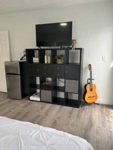 a entertainment center with a television and a guitar in a room at Nice and Cozy guest house 4 in Miami