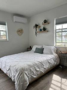 1 cama blanca en un dormitorio blanco con 2 ventanas en Nice and Cozy guest house 4, en Miami