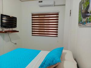 een slaapkamer met een bed, een televisie en een raam bij Teresita's House Suites 2 con cocina privada in Puerto Baquerizo Moreno