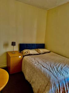 1 dormitorio con 1 cama con cabecero azul y mesa en Transformative housing birrell road en Nottingham