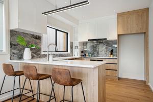 a kitchen with a counter and three stools at Devonport Beach Front Home in Auckland