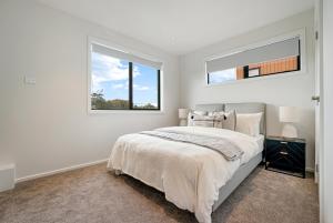 a white bedroom with a bed and a window at Devonport Beach Front Home in Auckland