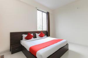 ein Schlafzimmer mit einem großen Bett mit roten Kissen in der Unterkunft Super OYO La Flora in Indore