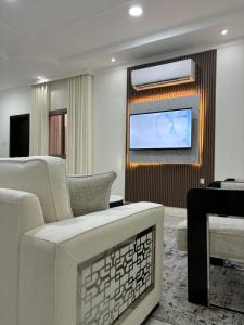 a living room with white furniture and a flat screen tv at MFAPARTMENT in Al Budayyiâ€˜