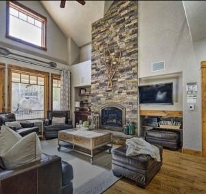 una gran sala de estar con chimenea de piedra. en Beautiful Red Feather Lakefront Home in Fox Acres!, en Red Feather Lakes