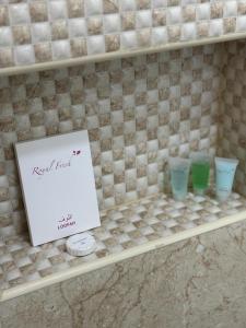 a shelf with four cups and a sign on it at MFAPARTMENT in Al Budayyiâ€˜ +2 photos