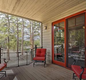 una silla roja sentada en un porche con una puerta de cristal en Beautiful Red Feather Lakefront Home in Fox Acres!, en Red Feather Lakes