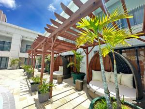 a wooden pergola with chairs and palm trees on a patio at Royal Orchid Hotel Guam in Tumon
