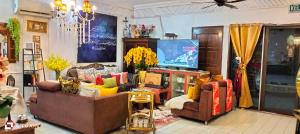 een woonkamer met 2 banken en een televisie bij Forest Paradise Inn Teluk Bahang PRIVATE MALAY TRADITIONAL HOUSE CONCEPT HOTEL in Teluk Bahang