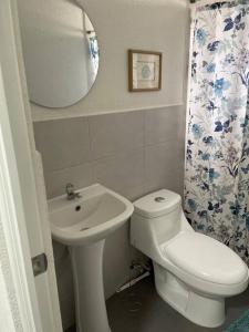 een badkamer met een wastafel, een toilet en een spiegel bij Apartamento cómodo y exclusivo in Villa Nueva