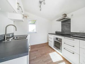 a kitchen with white cabinets and a sink at Hh-the Old Chippy in Codford