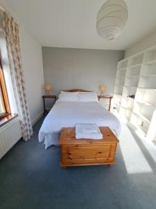 1 dormitorio con cama blanca y mesa de madera en House in the countryside en Cork