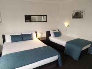 dwa łóżka w pokoju hotelowym z dwoma w obiekcie Alexander Motel w mieście Taumarunui