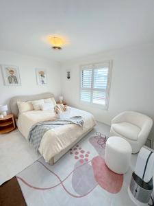 1 dormitorio blanco con 1 cama y 1 silla en Minimalist room in Bonython Not Entire Unit en Tuggeranong