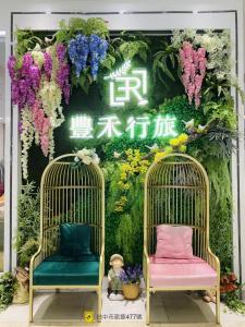 Taichung EnrichLife Hotel في تايتشونغ: كرسيان أمام جدار من الزهور