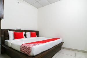 una camera da letto con un grande letto con cuscini rossi di OYO Hotel Rk Inn a Ludhiana