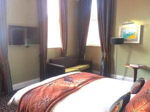 um quarto de hotel com uma cama e uma cadeira em The Last Post Wetherspoon Hotel em Southend-on-Sea