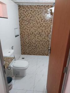 a bathroom with a toilet and a wooden wall at Casa simples e aconchegante / Banho quente in Contagem