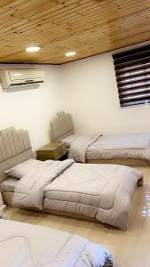 1 dormitorio con 3 camas y techo de madera en شاليه نايا, en Kerak