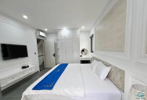 a white bedroom with a large bed and a tv at Royal Beach Villa Sonasea Vân Đồn Quảng Ninh 