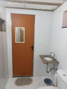 a bathroom with a brown door and a sink at Casa simples e aconchegante / Banho quente in Contagem