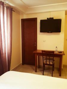 a bedroom with a table and a television on the wall at Hannatel Rooms Liberté in Douala