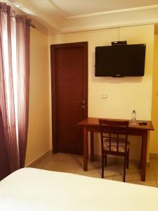 a bedroom with a table and a television on the wall at Hannatel Rooms Liberté in Douala