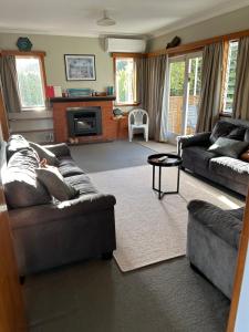 a living room with two couches and a fireplace at Rest & Relax Villa Whangarei in Whangarei