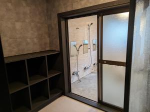 uma porta de vidro que leva a uma casa de banho com chuveiros em Tanigawa Valley Lodge & Coffee Roastery em Minakami