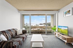 雪梨的住宿－Apartment with Pool Access, a minute to the Beach，带沙发和大窗户的客厅