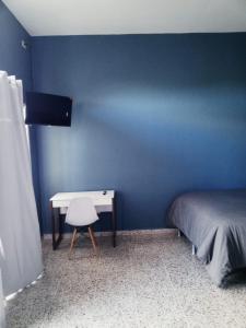 Dormitorio azul con cama y escritorio en Habitación con balcón en una Mansión, en Tegucigalpa