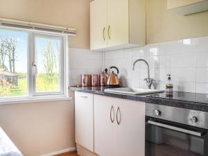 a kitchen with white cabinets and a sink and a window at Ponderosa in Llanstephan