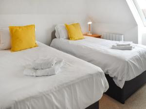 two beds with white sheets and yellow pillows at The Hayloft - Uk46186 in St Margarets at Cliff