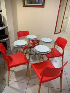 a table with red chairs and white plates on it at Cozy and relaxing apartment in Guatemala