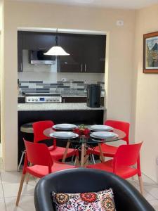 a kitchen with a table and red chairs in a room at Cozy and relaxing apartment in Guatemala