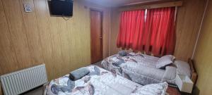 a bedroom with two beds in front of a window at Hostal Prat II in Valdivia