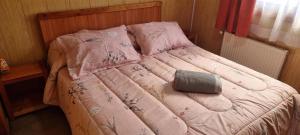 Una cama con un edredón rosa y una almohada. en Hostal Prat II en Valdivia