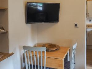 a table with a chair and a television on a wall at The Tack Room Cottage 