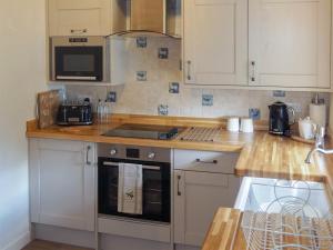 a kitchen with white cabinets and a stove top oven at The Tack Room Cottage 