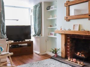 a living room with a television and a fireplace at Chapel Street Cottage in Amlwch